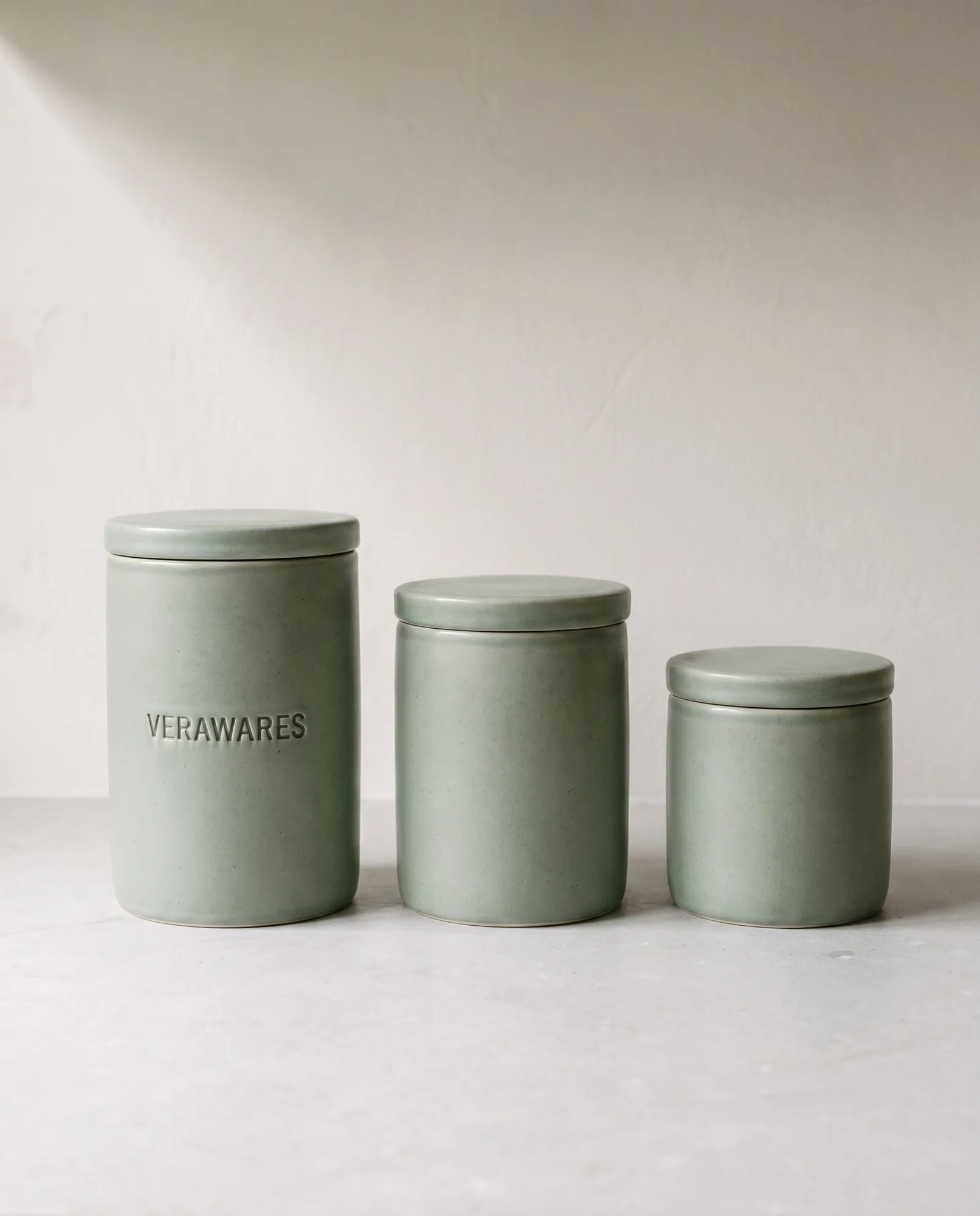 Canister Set — Three sage stoneware canisters with sealing lids